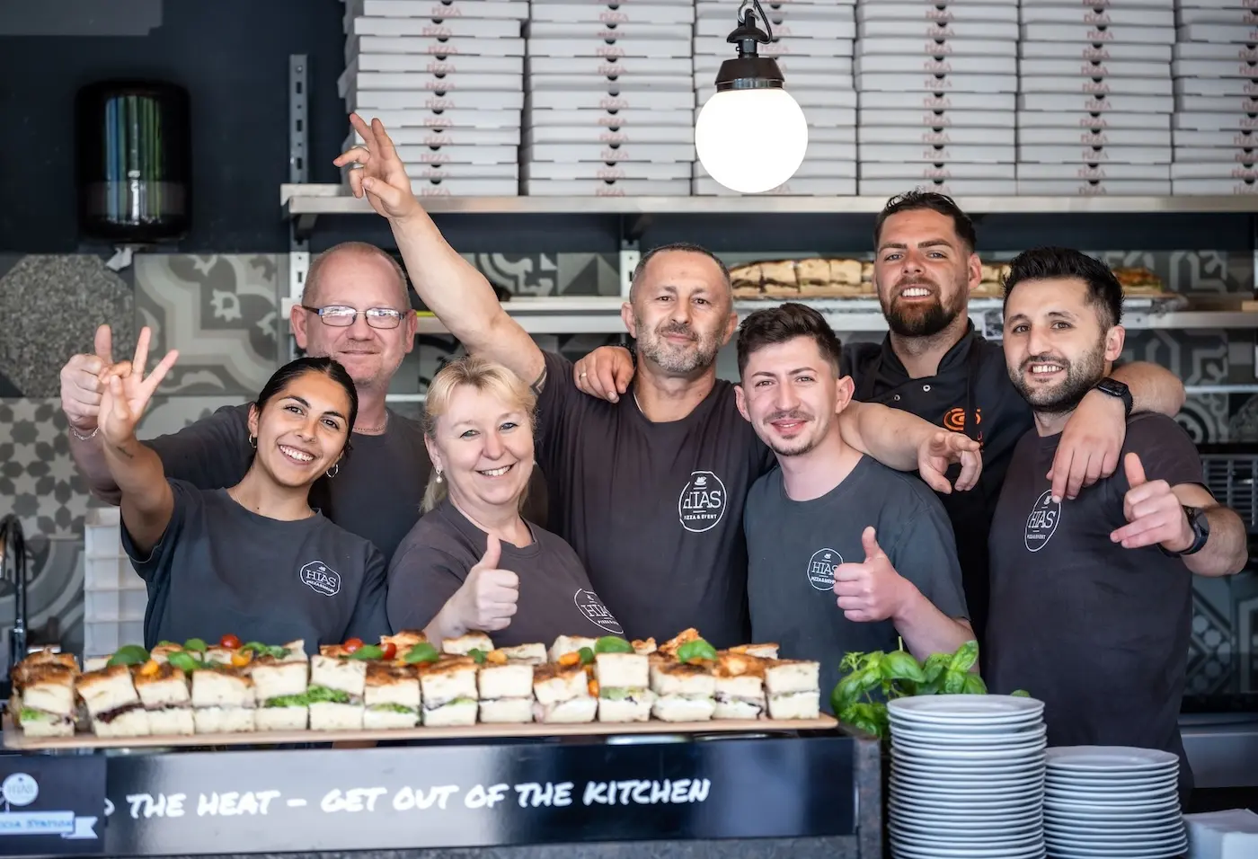Lächelndes Gastronomieteam hinter dem Tresen einer Pizzeria – Symbolbild für motivierte Mitarbeitende durch klare Aufgabenorganisation